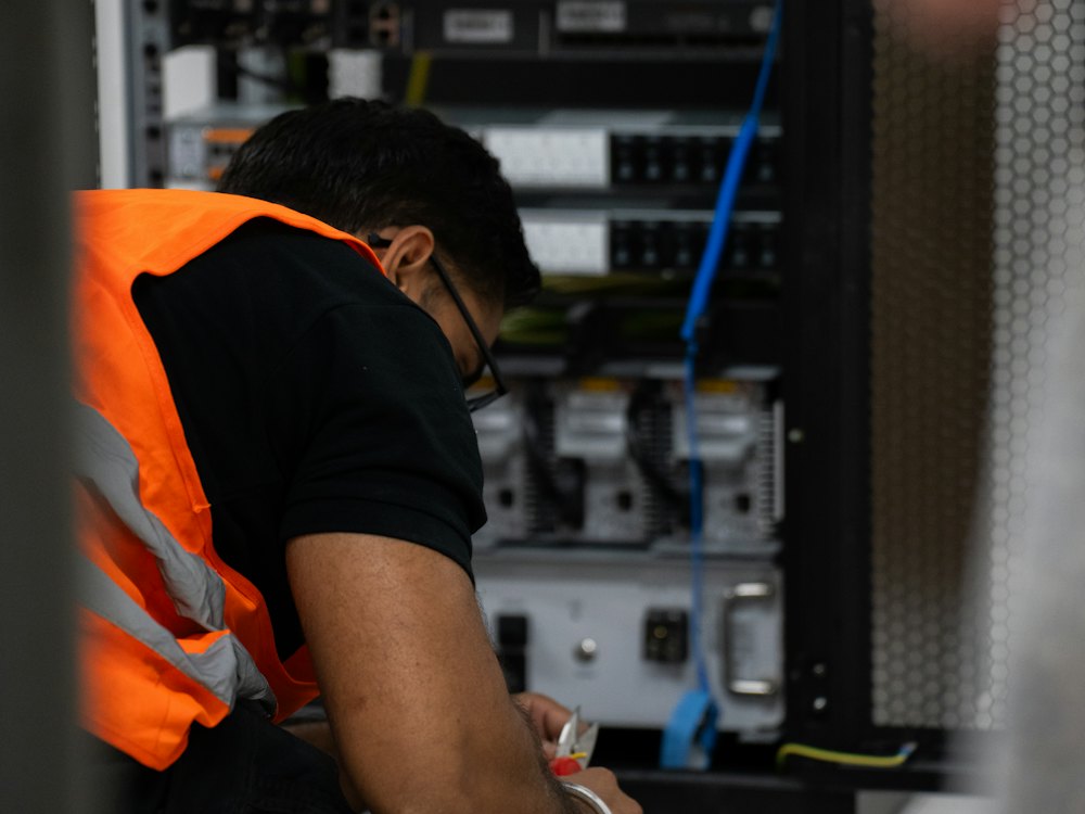 Technician in a safety vest working on network equipment